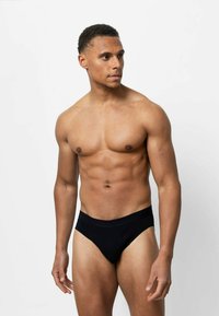 Zwarte herenslips gemaakt van zachte, rekbare stof. Lage taille met een snaarloze band. Aansluitende pasvorm, minimale naden en geen zichtbare patronen.