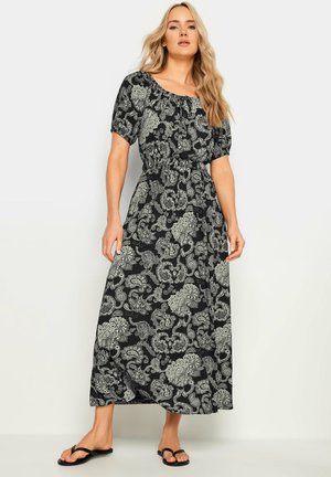 Vestido largo negro con patrón de paisley blanco, que presenta un escote en forma de barco, mangas cortas con volumen y una cintura elástica para una silueta ajustada.