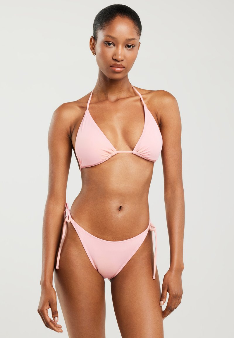 Różowy zestaw bikini z trójkątnym stanikiem na szyję oraz odpowiadającymi mu majtkami o niskim stanie z wiązaniami po bokach. Gładki, elastyczny materiał.