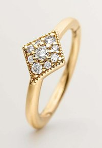 Anillo de oro con una parte superior en forma de cuadrado que presenta un grupo de piedras transparentes de corte redondo, rodeadas por una banda de oro texturizada.