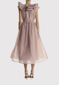 Rosa midi-kjole med rynkede skuldre, samlet talje og semigennemsigtigt stof. Sammen med beige højhælede sandaler.
