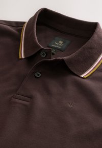 Mørkebrun polo-shirt med tekstureret stof, der har en kontrastfuld, stribet krave i creme, gul og lilla, samt et logo på brystet.