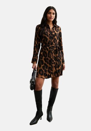 Vestido de botón con estampado de leopardo, cintura ceñida con cinturón, mangas largas y corte holgado, combinado con botas de tacón alto negras hasta la rodilla.