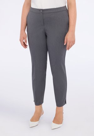 Pantaloni grigi su misura con vestibilità slim, tessuto morbido e spacchi alle caviglie. Abbinati a décolleté bianchi a punta, che offrono un aspetto elegante.