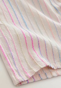 Tissu en coton avec des rayures verticales rose, bleu et crème. Il présente une surface texturée avec des coutures décoratives le long des bords.
