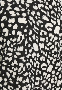 Tissu à motifs noir et blanc présentant des taches de léopard irrégulières, avec une texture douce et un poids moyen, adapté à des vêtements élégants.