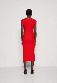 Punainen midi-mekko, jossa on lyhyet hihat, sileä rakenne ja hieman joustava materiaali. Yhdistetty mustiin pyöreäkärkisiin kenkiin, nähty takaapäin.