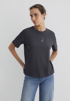 Dunkelgraues T-Shirt mit kurzen Ärmeln aus weicher Baumwolle. Verfügt über ein kleines, weißes gesticktes Hundedesign auf der Brust. Lässiger Schnitt und runder Ausschnitt.