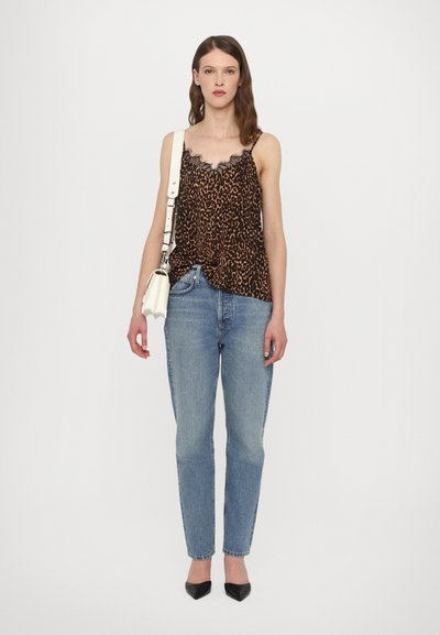 Cheetah-print top met zwarte kantafwerking, gecombineerd met lichtblauwe rechte jeans en zwarte puntige hakken; witte schoudertas.