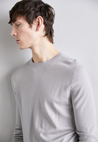 Chemise grise à manches longues avec un col rond, fabriquée en tissu lisse, dotée d'une coupe décontractée et de détails de couture minimaux.