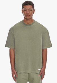 Olivengrøn oversized t-shirt lavet af blødt stof, med rund halsudskæring, korte ærmer og et lille logo-detalje på ærmet.