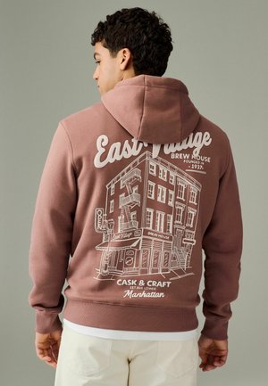 Brown hoodie with a white graphic of a building on the back, featuring text and details about a brew house, cotton material, casual fit.