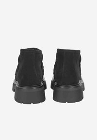 Bottines en daim noir avec une semelle en caoutchouc épaisse et une finition lisse. Bout arrondi et design simple, comportant des détails cousus à l'arrière.