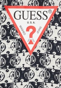 Camiseta de algodón con un patrón de logotipos repetidos en blanco y negro, con una etiqueta triangular roja destacada que muestra "GUESS" y detalles del producto.