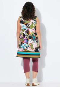 Bezramenná tunika v živém květinovém potisku s pruhovaným lemem, spárovaná s kaštanovými capri kalhotami a bílými kotníkovými botami. Hladká látka, pohodlný střih.