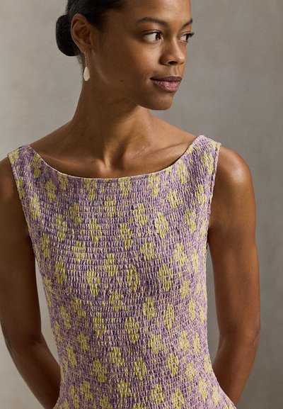 Φόρεμα σμόκ σε λεβάντα με υφή και κίτρινες λεπτομέρειες. Το φόρεμα διαθέτει φαρδύ ντεκολτέ και εφαρμοστή γραμμή.