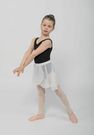 Schwarzer Body mit dünnen Trägern, schichtiger weißer Chiffonrock, hellrosa Ballettschuhe und beige Strumpfhosen. Kind in einer Ballettpose, neutraler Hintergrund.
