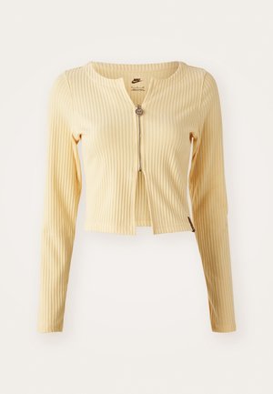 Yellow ribbed long-sleeve top with zippered front, cropped design, round neckline, and subtle texture. Brand tag visible inside neck.