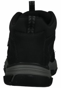 Las zapatillas deportivas negras cuentan con un upper suave con acentos texturizados, una suela gris y una lengüeta en la parte posterior para facilitar su uso.