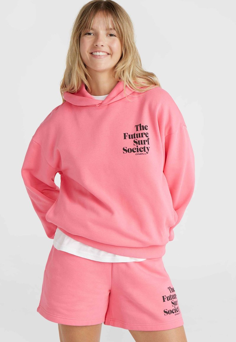 Set di felpa rosa e pantaloni corti realizzato in tessuto morbido. La felpa presenta una tasca frontale e un logo stampato in nero sul petto.
