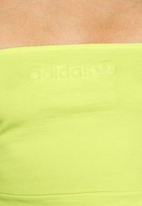 Grön bomullssporttop med elastisk tyg, en figursydd passform och präglad "adidas"-logotyp med en trefoil-accent.