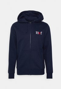 Námořnická mikina na zip vyrobená z měkké látky, se skrytým předním kapsou, kapucí se šňůrkou a vyšitým logem s červeným srdcem.