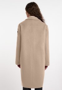 Beige wollen blend jas met een rechte snit, lange mouwen en een gesneden kraag. Voorzien van een naadloze achterkant en minimale hardware accenten.