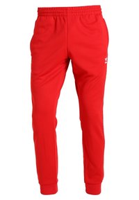 Röda träningsbyxor i syntetmaterial, med elastisk midja, avsmalnande ärmslut och en liten vit logotypdetalj.