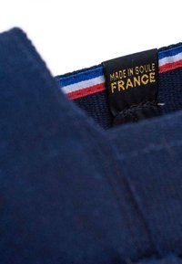 Tissu bleu marine avec une finition texturée, arborant une étiquette indiquant "FABRIQUÉ À SOULÉ FRANCE" en doré, accompagnée d'un band de tricolore (bleu, blanc, rouge).