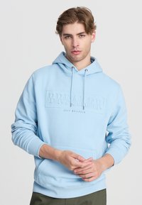 Felpa blu chiaro realizzata in tessuto morbido, con tasca a marsupio, cappuccio con lacci e testo in rilievo "BREAKER" sul davanti.