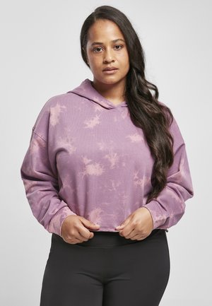 Lila Tie-Dye cropped Hoodie mit langen Ärmeln und einer frontalen Tasche, aus weichem Stoff. Über schwarzen Leggings getragen.