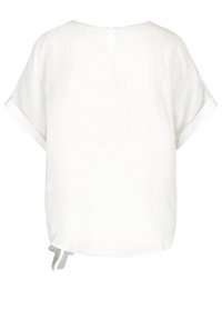 Haut en lin blanc à coupe décontractée, manches courtes, et fermeture au dos avec fente. Comprend des liens à l'ourlet pour un ajustement réglable.