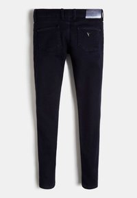 Pantalones vaqueros ajustados de color azul oscuro con bolsillos traseros, trabillas para cinturón y una etiqueta plateada de la marca Guess en la cintura.