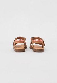 Tan lädersandaler med bakrem, öppen tå, glatt rosa innersole och texturerad yttersula. Har en enkel design med minimal detaljer.