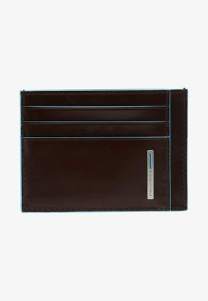Porte-carte en cuir marron avec des coutures bleues, six emplacements pour cartes et un accent logo argenté sur un côté. Texture lisse. Forme rectangulaire.