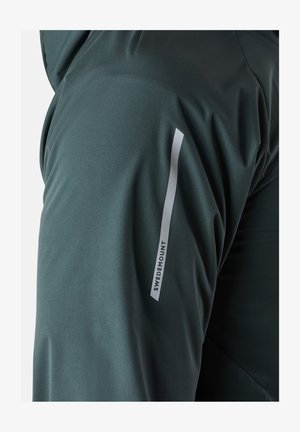 Dunkelgrüne, leichte Stoffjacke mit einer glatten Textur und einem weißen Logoetikett am Ärmel mit dem fett gedruckten Text "SWEDEMOUNT".