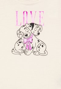 Camiseta de algodón con dos cachorros de dálmata ilustrados, un lazo rosa y la palabra "AMOR" en brillante color rosa encima de ellos, sobre un fondo crema.