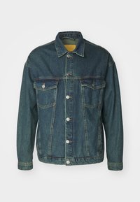 Spijkerjack in donkerblauw met een klassieke snit, voorzien van twee borstzakken, knoopsluiting en contraststiksels langs de naden.