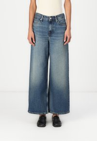 Φαρδιά μπλε τζιν παντελόνια με ξεθωριασμένο φινίρισμα, διαθέτουν κλασικό σχέδιο πέντε τσεπών και ίσια γραμμή. Το υλικό είναι τζιν με απαλή υφή.