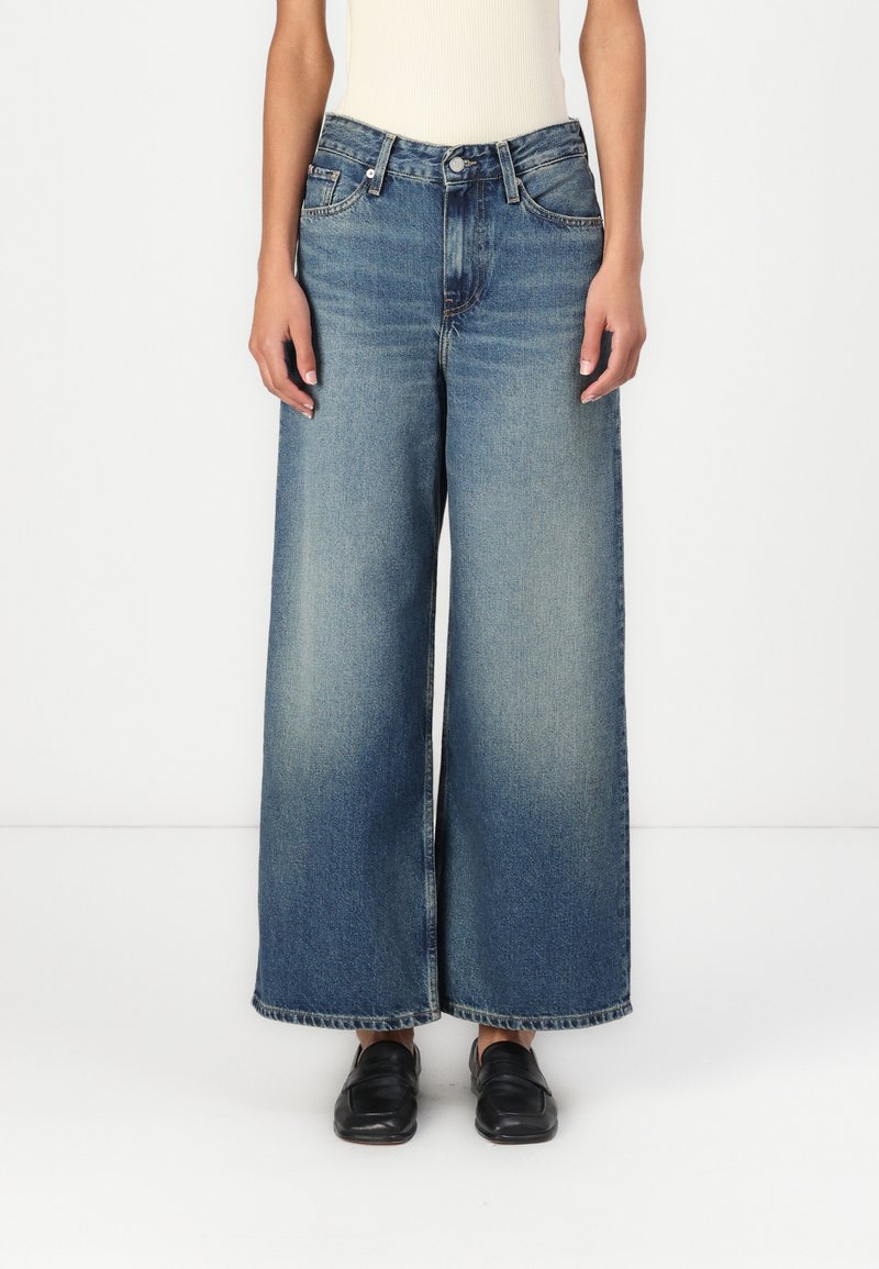 Φαρδιά μπλε τζιν παντελόνια με ξεθωριασμένο φινίρισμα, διαθέτουν κλασικό σχέδιο πέντε τσεπών και ίσια γραμμή. Το υλικό είναι τζιν με απαλή υφή.