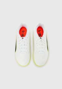 Λευκά παπούτσια ποδοσφαίρου με υφή στο σχέδιο, μαύρες λεπτομέρειες και έντονη κίτρινη σόλα. Διαθέτουν κορδόνια, επενδυμέ νο κολάρο και ζωντανή εσωτερική επένδυση.