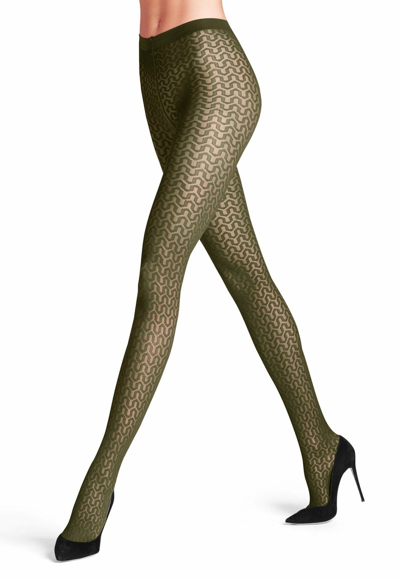 Des collants olive à motif présentent un design en vagues, avec une texture semi-transparente et une taille confortable. Portés avec des talons hauts noirs.