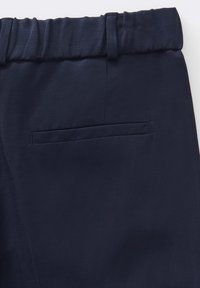 Pantalon bleu marine en tissu texturé, avec une taille plate, des passants de ceinture et une poche arrière unique.