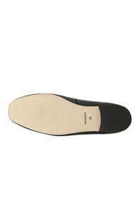 Suola di scarpa nera con una finitura beige liscia, caratterizzata da una leggera texture scanalata per una migliore aderenza. Il marchio e la taglia "38" sono visibili.