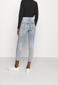 Ljusblå skinny jeans i denim, med medelhög midja, fem fickor och en subtilt blekt struktur. Bärs med vita sneakers.