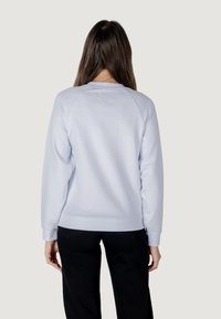 Sudadera de algodón azul claro con cuello redondo, puños y dobladillo de canalé, que presenta una textura suave y mangas raglán.