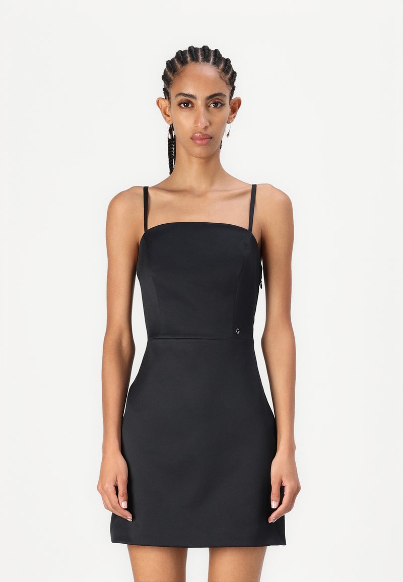 Robe mini noire ajustée avec des fines bretelles, décolleté carré et texture lisse. Présentant un petit logo près de la taille.