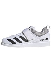 Zapatilla deportiva blanca con parte superior de malla, presenta acentos de rayas negras, una correa de velcro y un contrafuerte texturizado en el talón para mayor soporte.