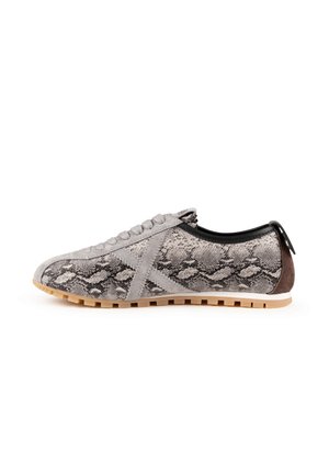 Zapatilla de perfil bajo con patrón de piel de serpiente en gris y negro, suela beige, detalles en ante gris y parche marrón en el talón, vista lateral sobre fondo blanco.