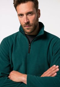 Türkisfarbener Fleece-Pullover mit hohem Kragen und einem Viertelreißverschluss. Weicher Stoff mit langen Ärmeln und minimalistischem Design. Keine sichtbaren Logos oder Muster.